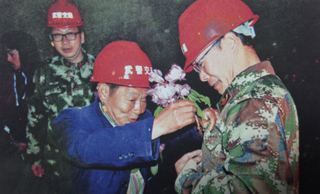 高德荣给独龙江隧道施工队官兵戴上“英雄花”。